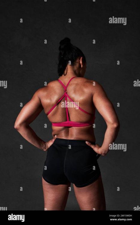 back-view-of-unrecognizable-strong-female-with-perfect-sportive-body-wearing-red-top-and-shorts-standing-on-black-background-2M15WDH.jpg